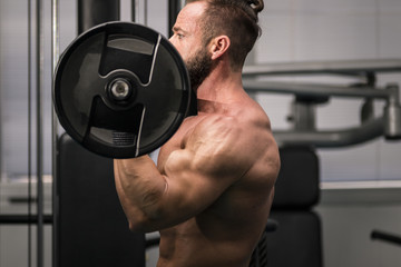 Hombre fuerte con grandes músculos levantando peso mientras entrena en el gimnasio. Ponerse en...