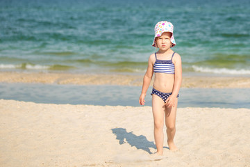 Little cute blonde girl walking away from sea