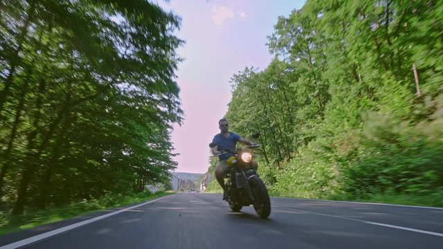 modern custom scrambler motorbike on a forest road riding. having fun driving the empty road on a motorcycle tour journey. 4k Video