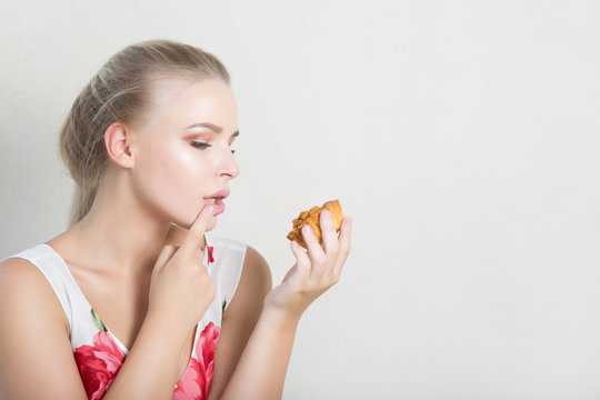 Pleased blonde woman with natural makeup holding savory dessert with nuts. Space for text
