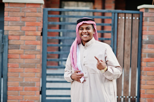 Middle Eastern arab man posed on street against modern building and showing finger.