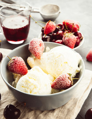 Vanilla ice cream in a grey bowl. Homemade organic dessert with jam, sweet cherry and strawberry. Top view