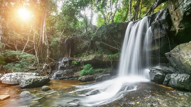 Beautiful mountain waterfall in the jungle forest. Water slow flow and fall down from high mossy rock. Green tree tropical foliage in sunset soft light. Zoom. 4K Slow Motion Photo Time Lapse Parallax