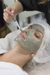 Young beautiful girl receiving lifting facial mask in spa beauty salon - indoors