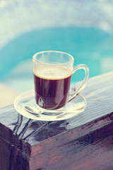 A cup of espresso and a pool in the background. Morning coffee. Summer Breakfast.