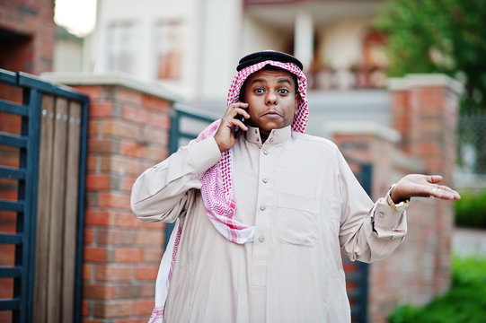 Middle Eastern arab business man posed on street against modern building with mobile phone and showing surprise emotions.
