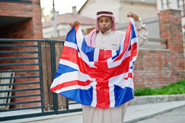 Middle Eastern arab man posed on street with Great Britain flag. England and Arabian countries...