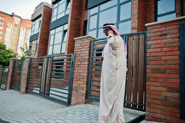 Fototapeta na wymiar Middle Eastern arab business man posed on street against modern building with sunglasses, speaking on mobile phone.