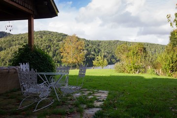 Outdoor white iron table, four chairs on big yard with mountains on the background in Valdivia,...