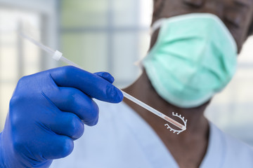 Afro-American doctor holding an IUD birth control copper coil device in hand