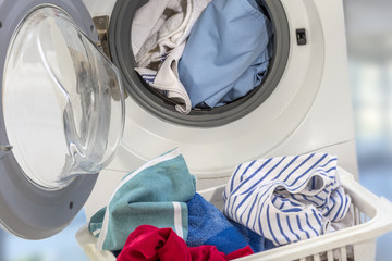 Full Washing machine and clothes in basket on white background