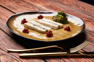 Slice of Fresh Brie cheese with truffle and jelly barberry. Delicious dish with red wine, champignons mushrooms and truffle oil at the restaurant table. Vegetarian delicacy diet food
