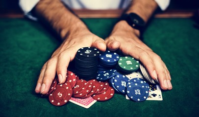 Closeup of hands with gambling tokens and card