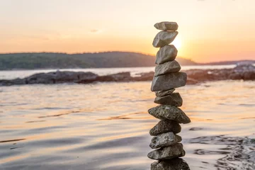 Photo sur Plexiglas Côte Zen balanced stones stacked on sea coast at sunset. Balance and equilibrium concept.