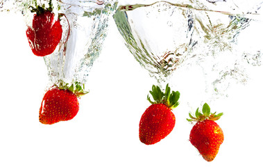 Red strawberries dropped into the water with splash on a white background