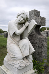 Grabfigur einer trauernden Frau mit Kreuz