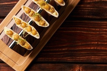 Labne and karri snack food with fried yellow peas, curry, lemon peel, in bread cake pita. Delicious vegetarian food on silver stand at luxury restaurant table, top view