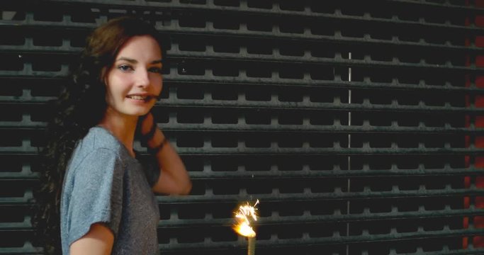 Girl Having Fun With Sparkler In The Street In Front Of Metal Fence