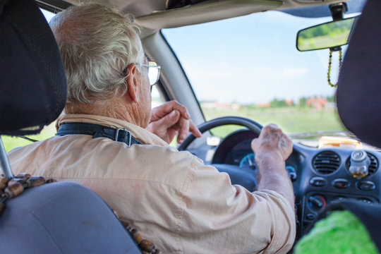 An Elderly Man Is Driving A Car