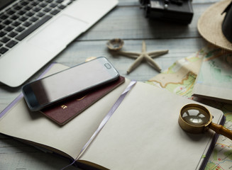 Travel planning concept, notebook, map, documents, hat, laptop, camera, accessories for trip, outfit of traveller, tourist making his notes, selective focus