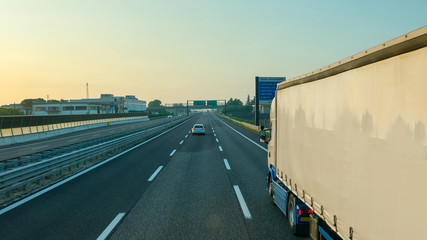 White truck driving motorway at sunrise, transportation background