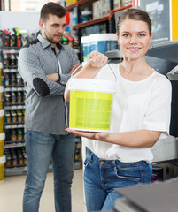 Young woman standing near man and holding bucket of paint © JackF