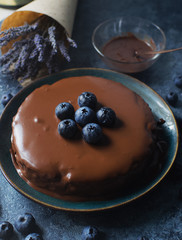Homemade blueberry cheesecake with chocolate topping and fresh organic berries, lavender on a dark stone background. Selective focus