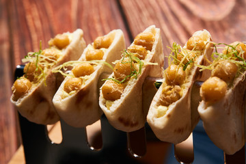 Labne and karri snack food with fried yellow peas, curry, lemon peel, in bread cake pita. Delicious vegetarian food on silver stand at luxury restaurant table, top view