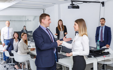 businessman and businesswoman shaking hands in office