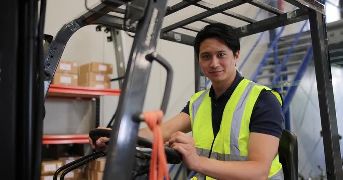 Portrait of male working in distribution warehouse on a forklift 