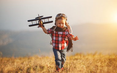 Child pilot aviator with airplane dreams of traveling in summer  at sunset