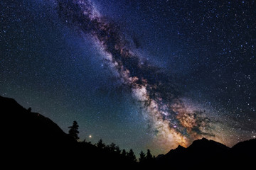 Astrophotography of Milky Way galaxy. Silhouette of mountains. Stars, nebula and stardust at night sky landscape - obrazy, fototapety, plakaty