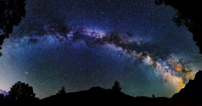 Panoramic astrophotography of whole visible Milky Way galaxy. Silhouette of mountains. Stars, nebula and stardust at night sky landscape