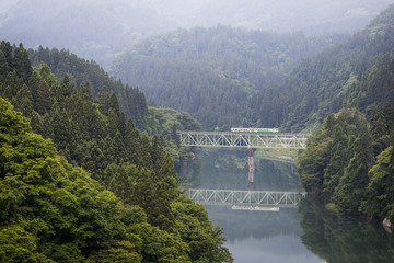 Fukushima , JAPAN - June 19 : The local train Tadami line and Tadami river on June 18 , 2017 in Fukushima , Japan. This train services in East Japan railway company's Tadami line.