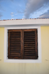 Window and sun shutters on a traditional Croatian home with the view of a sunset, Korcula island, Croatia, June 2018