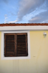 Window and sun shutters on a traditional Croatian home with the view of a sunset, Korcula island, Croatia, June 2018