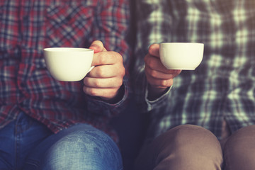 couple with two cups of morning coffee in plaid shirts