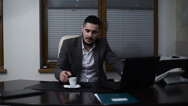 Attractive senior businessman drinking coffee at workplace
