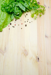 Basil and salad and dill next to pepper peas on wooden background 