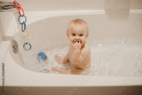 Adorable Blonde Baby Boy Playing And Smiling In The Bath Tub