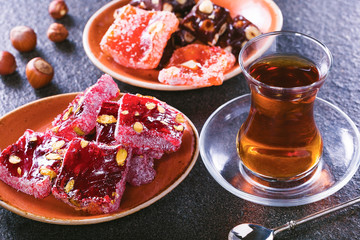 Traditional Turkish tea with traditional oriental sweet on brown  surface.Turkish desert-Rahat lokum.