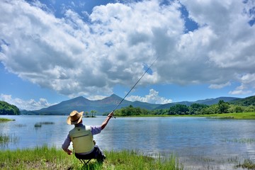 夏の湖畔・のんびりと釣りをする男性