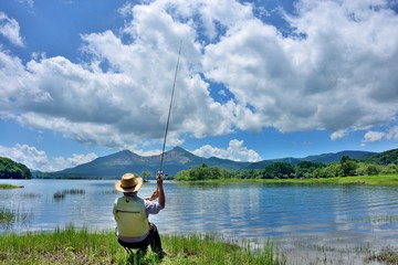 夏の湖畔・のんびりと釣りをする男性