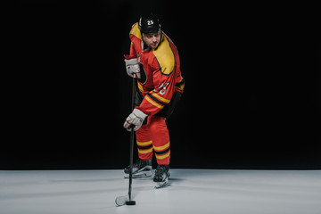 Fototapeta premium full length view of professional sportsman in skates playing ice hockey on black