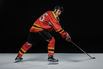 Obraz premium young professional sportsman playing ice hockey on black