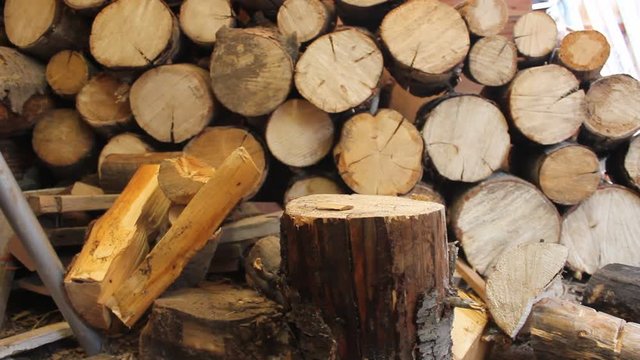 A wood  log is simply split in half with a axe next to a pile of wood for keeping warm in the winter.