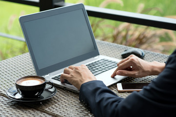 business man sitting at table in coffee shop. On table is laptop, smartphone and cup of coffee