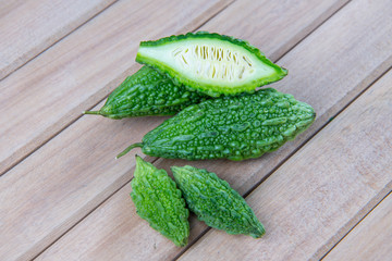 Closeup view of bitter gourd over wooden board background.