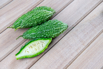 Closeup view of bitter gourd over wooden board background.