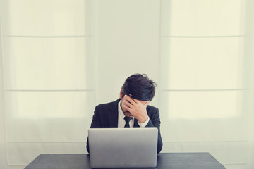 Tired frustrated business people feeling stressed, upset executives sitting near laptop, holding head in hands, worried about business problem failure, depressed by bad news,